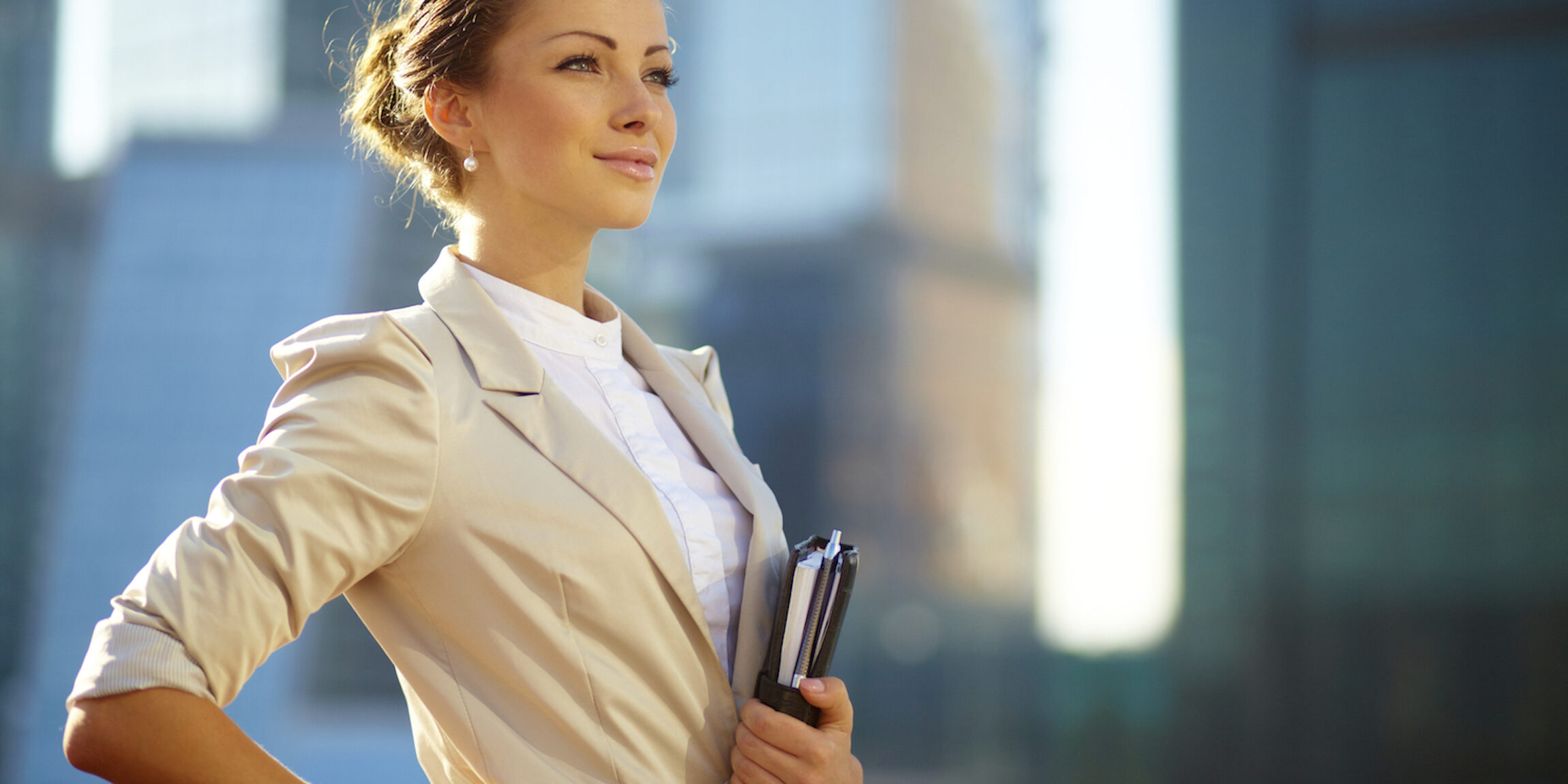 Fotografia de uma jovem mulher de negócios segurando pastas com fundo de prédios