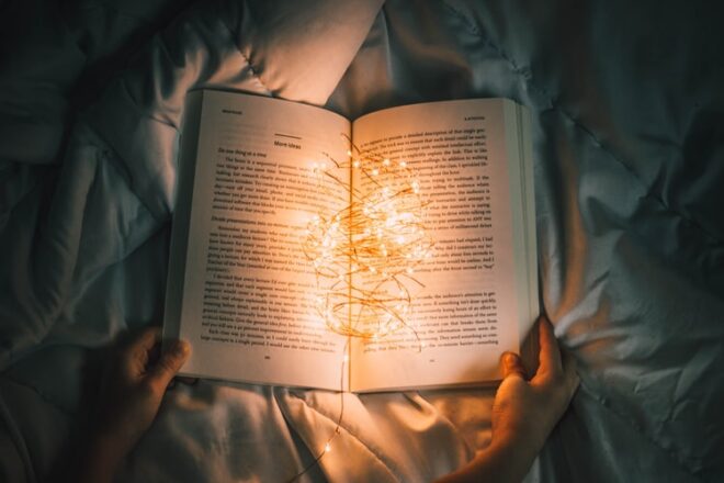 Livro aberto com luzes em cima, indicando a iluminação que pode surgir com os livros